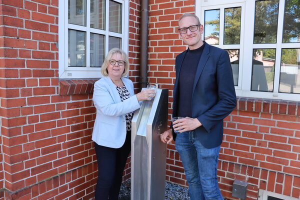 Zapfen ein Glas Wasser vom neuen Trinkwasserspender: B&uuml;rgermeisterin Gabriele Hettwer und Sven Dutschmann, Fachbereichsleiter der Stadt Bargteheide.